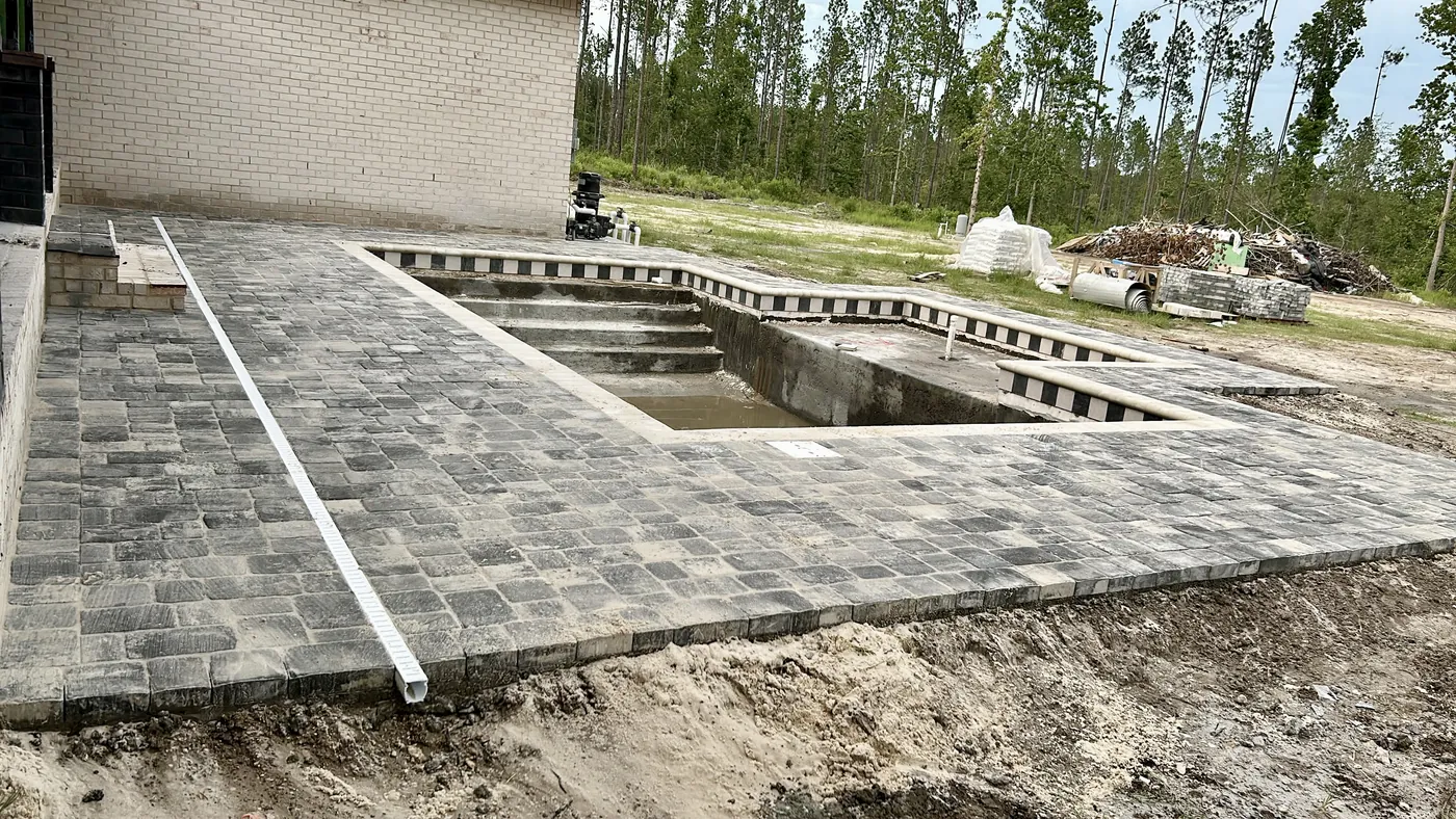 Paver deck installed around an unfinished pool